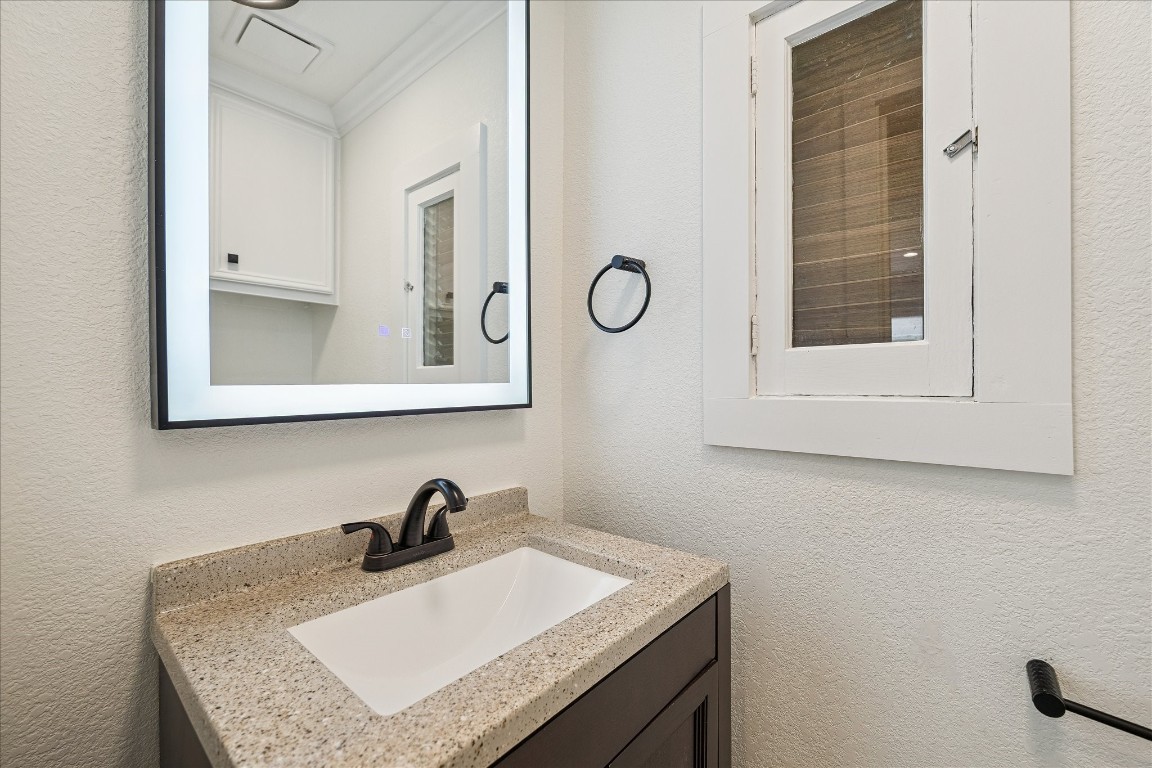 3071 Locke Lane Houston, TX 77019 - Photo 22 of 44 The powder room is both stylish and functional, featuring an undermount sink with a storage cabinet below and a backlit mirror with additional storage above the commode, combining convenience with modern design.