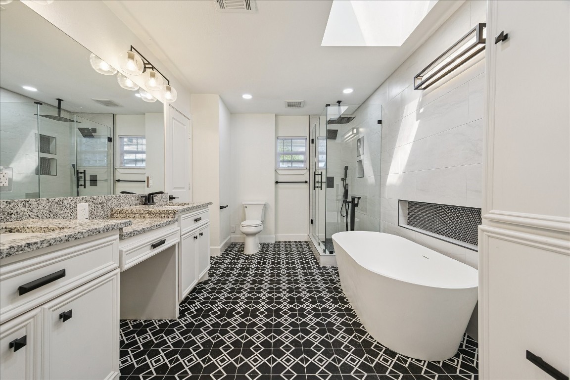 3071 Locke Lane Houston, TX 77019 - Photo 27 of 44 This primary bathroom features designer tile flooring, granite countertops, and a luxurious soaking tub, creating a spa-like retreat. The walk-in shower includes a rainfall showerhead and shower wand for a versatile, relaxing experience.