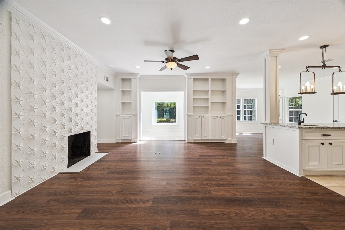 3071 Locke Lane Houston, TX 77019 - Photo 3 of 44 The family room, open to the kitchen, sunroom, and dining area, boasts neutral designer wall paint, a fireplace with custom tile surround, ceiling fan, and built-in cabinetry. Elegant crown molding completes this inviting space, perfect for daily living and entertaining.