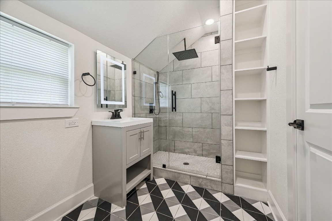 3071 Locke Lane Houston, TX 77019 - Photo 31 of 44 The guest suite #1 bathroom features designer tile flooring, a walk-in shower with rainfall showerhead, and an undermount sink with storage below. A backlit mirror adds both style and functionality, creating a modern and well-appointed space for guests.