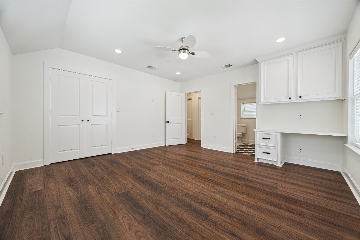3071 Locke Lane Houston, TX 77019 - Photo 32 of 44 From another perspective, the junior primary suite showcases its multiple closets and versatile layout, with an ensuite bath, neutral paint, and a built-in desk. Windows fill the space with natural light, creating a bright and functional retreat.