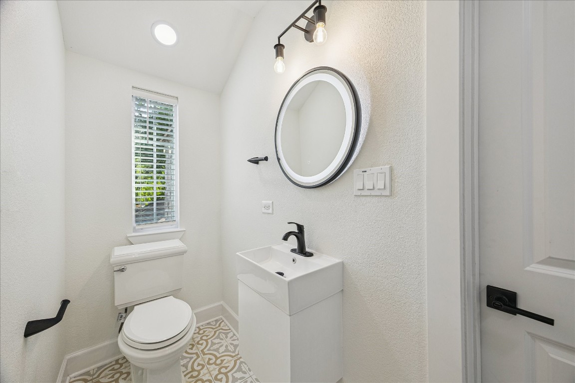 3071 Locke Lane Houston, TX 77019 - Photo 34 of 44 The shared bathroom features tile flooring, a walk-in shower, and vanity lighting over the sink. A window provides natural light, creating a bright and functional space for the adjacent bedrooms.