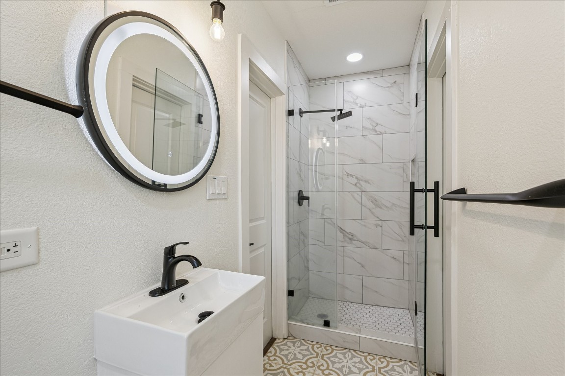 3071 Locke Lane Houston, TX 77019 - Photo 35 of 44 This view of the shared bathroom highlights the walk-in shower with tile surround and sleek matte black hardware, combining modern style with practical functionality for everyday use.