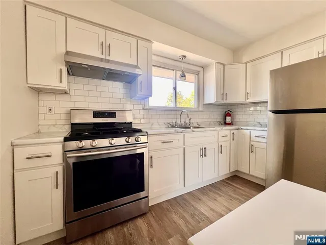 a kitchen with cabinets stainless steel appliances a sink and wooden floor