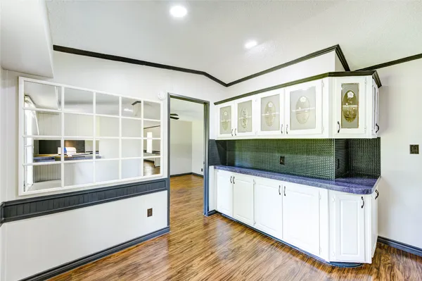 a living room with stainless steel appliances kitchen island granite countertop a sink and a wooden floor