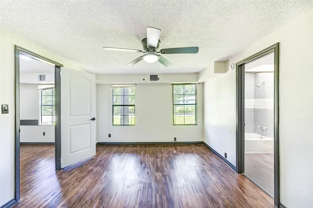 a view of empty room with wooden floor and fan