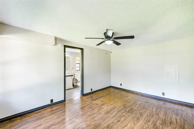 an empty room with wooden floor cabinet and windows
