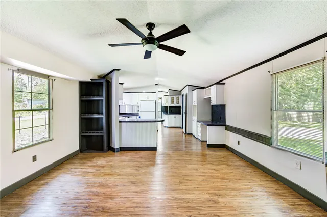 a view of a livingroom with furniture a ceiling fan and wooden floor
