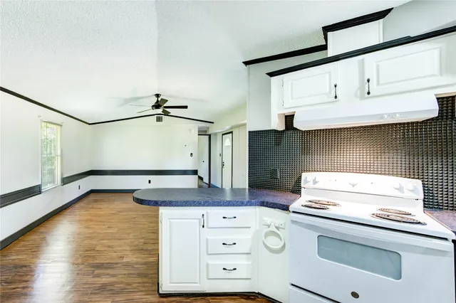 a kitchen with a stove cabinets and wooden floor