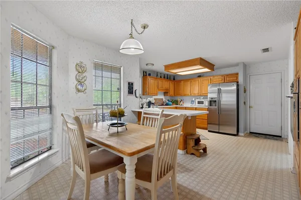 a kitchen with stainless steel appliances kitchen island granite countertop a refrigerator a stove a sink dishwasher and a dining table with wooden floor