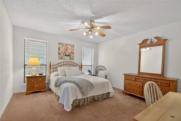 a spacious bedroom with a bed a chandelier and a dresser