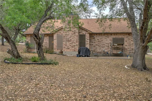 a view of a brick house with a small yard and large tree