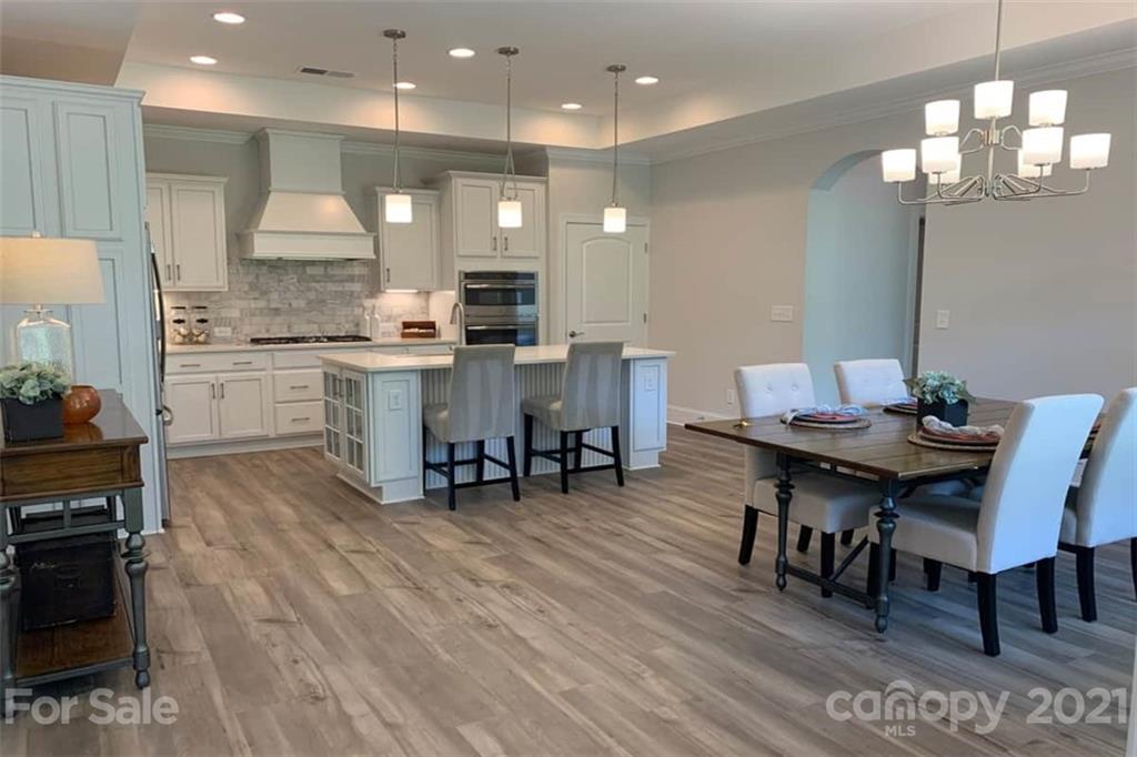 2070 New Style Way, Unit 39 Tega Cay, SC 29708 - Photo 4 of 12 a kitchen with stainless steel appliances granite countertop a stove a refrigerator a kitchen island a dining table and chairs with wooden floor