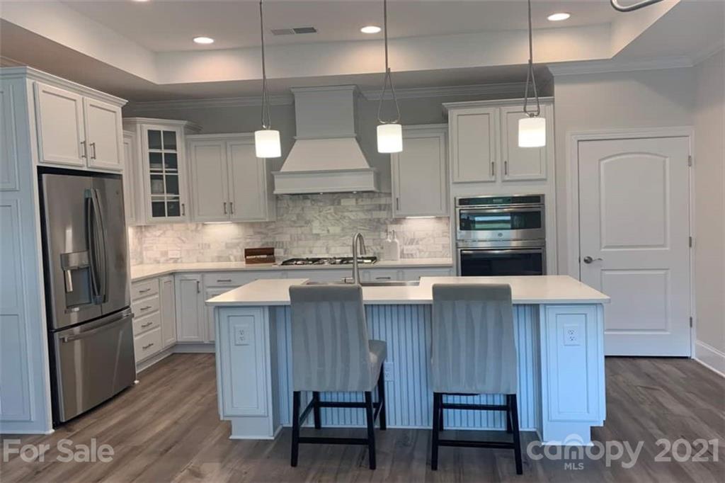 2070 New Style Way, Unit 39 Tega Cay, SC 29708 - Photo 5 of 12 a kitchen with kitchen island granite countertop wooden cabinets and refrigerator