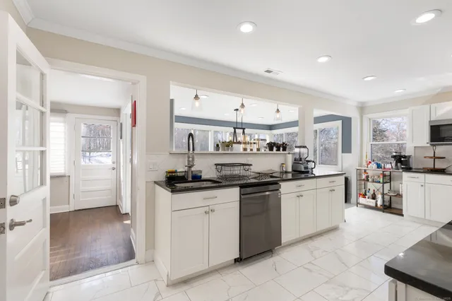 a kitchen with stainless steel appliances granite countertop a stove top oven a sink a refrigerator and white cabinets with wooden floor