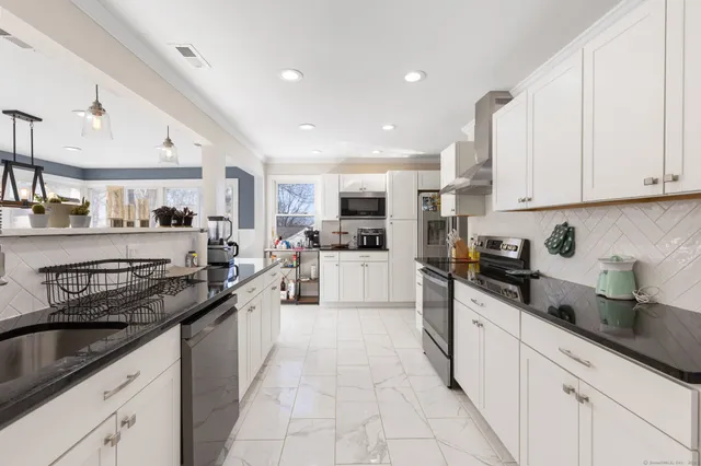 a large kitchen with stainless steel appliances granite countertop a sink and cabinets
