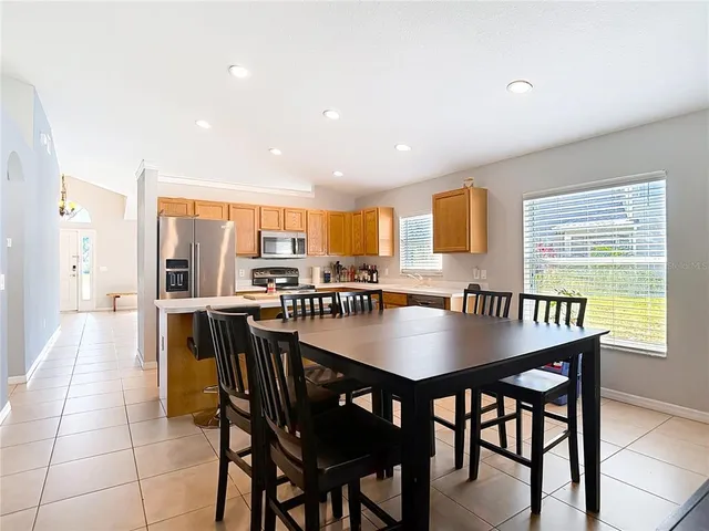 a kitchen with stainless steel appliances a sink a stove a refrigerator cabinets and chairs