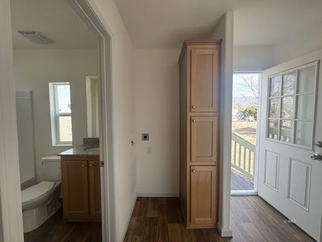 a view of a hallway with wooden floor and a bathroom