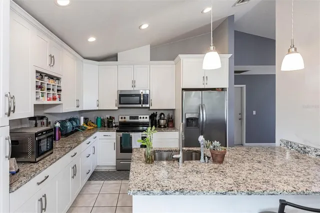 a kitchen with stainless steel appliances kitchen island granite countertop a refrigerator oven a sink and dishwasher