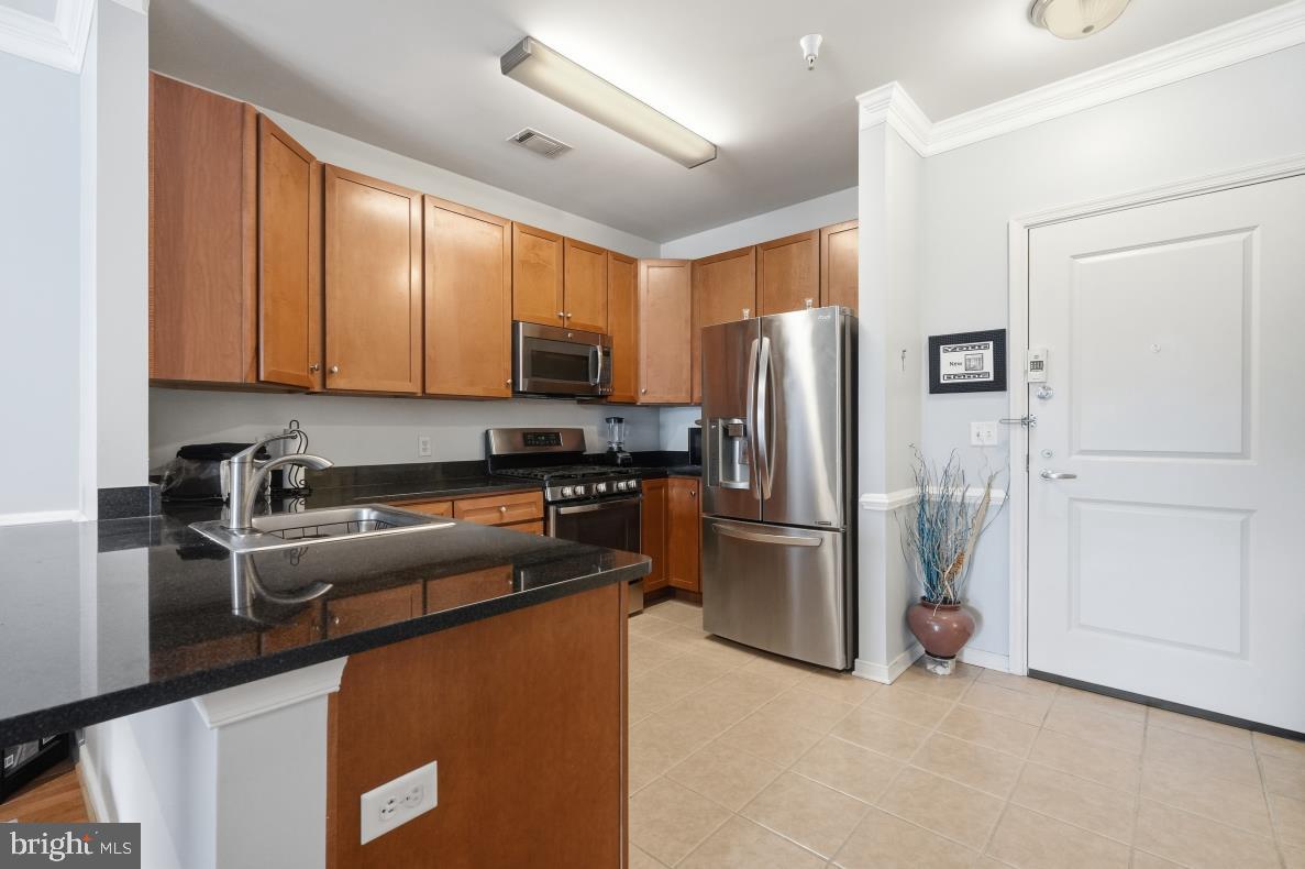 8045 Newell Street, Unit 423 Silver Spring, MD 20910 - Photo 15 of 26 a kitchen with stainless steel appliances granite countertop a refrigerator a stove top oven a sink and dishwasher