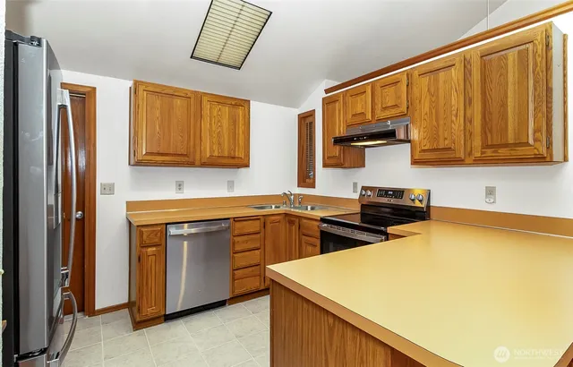 a kitchen with stainless steel appliances granite countertop a stove a sink and a microwave