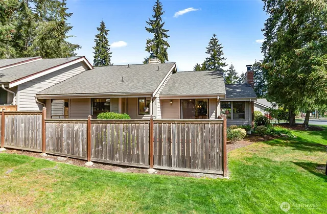 a white house with a small yard and large trees