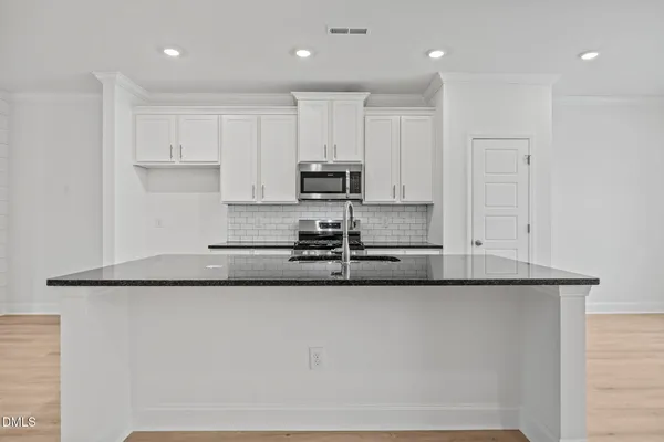 a large kitchen with granite countertop a sink and dishwasher a stove top oven with wooden floor