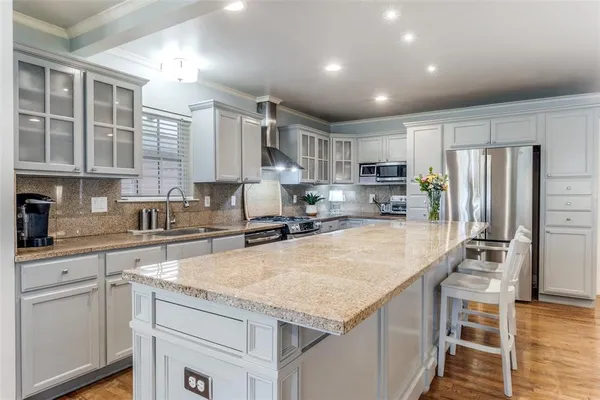 a large kitchen with kitchen island a large counter top stainless steel appliances and cabinets