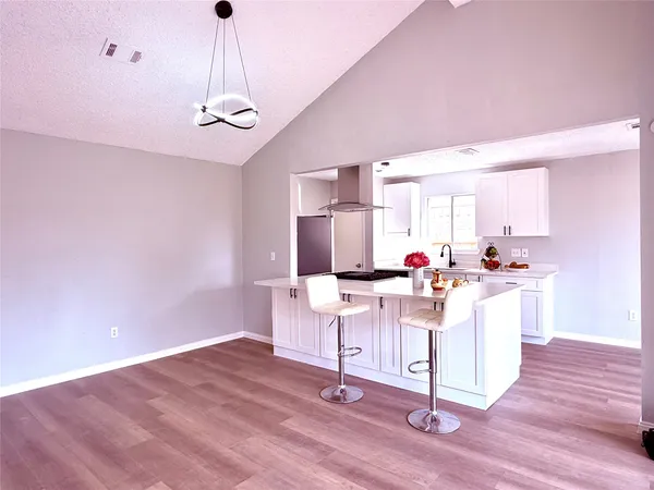 a view of a kitchen with kitchen island stainless steel appliances wooden floor and a chandelier