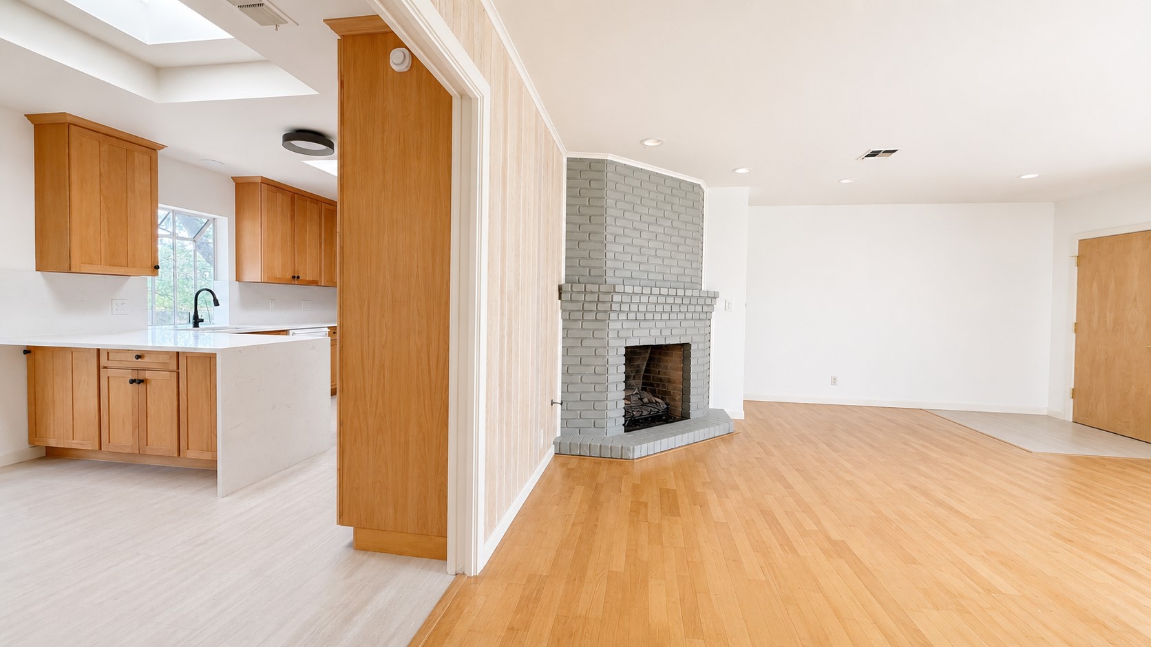 405 Ridgewood Road Austin, TX 78746 - Photo 4 of 22 Open-concept living area featuring light wood-finish flooring, a painted brick fireplace, and white walls