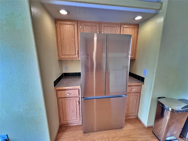 a view of a refrigerator in kitchen and an empty room