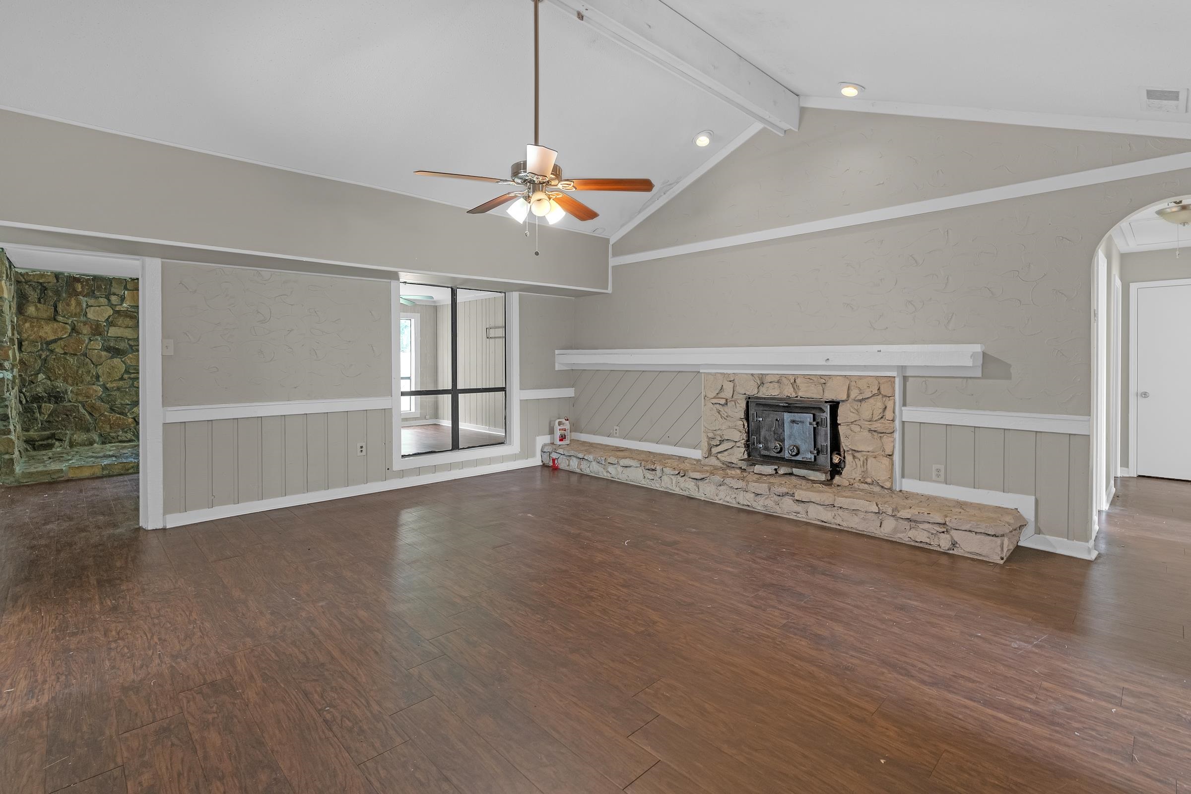 6128 Raintree Drive Memphis, TN 38115 - Photo 4 of 30 Unfurnished living room with a fireplace, a wainscoted wall, beam ceiling, ceiling fan, and dark wood-type flooring