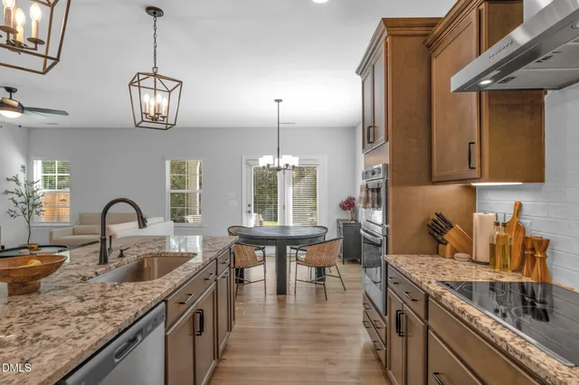 a kitchen with stainless steel appliances granite countertop a sink a stove and a wooden floors