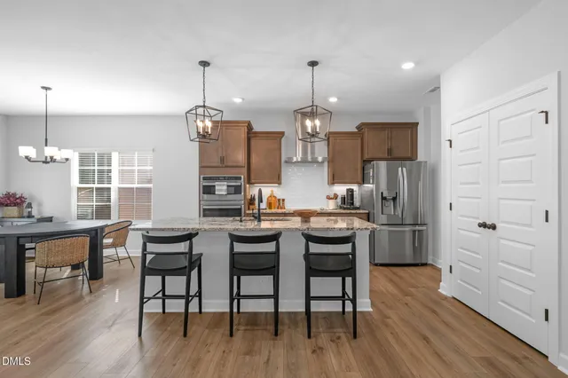 a kitchen with stainless steel appliances kitchen island granite countertop a table chairs stove and refrigerator