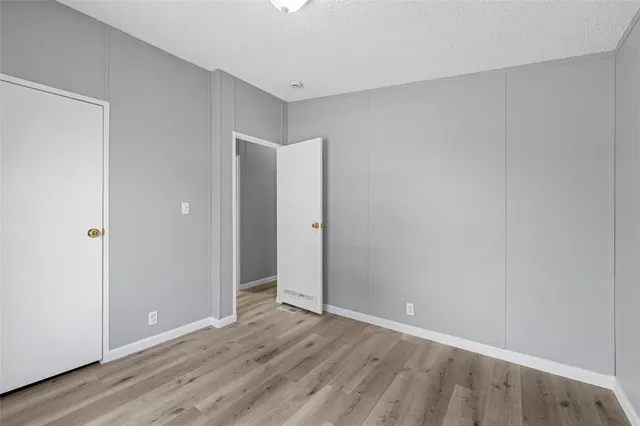 a view of an empty room with wooden floor and closet