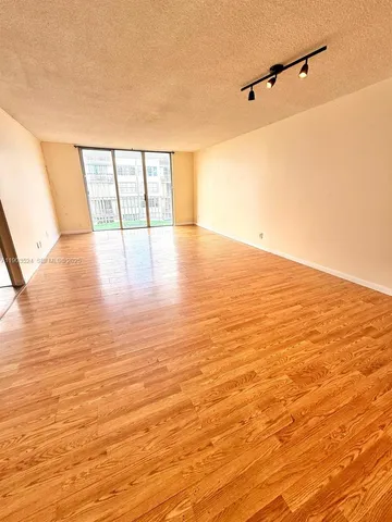a view of an empty room with wooden floor and windows
