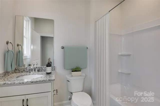 a bathroom with a granite countertop sink a toilet and shower