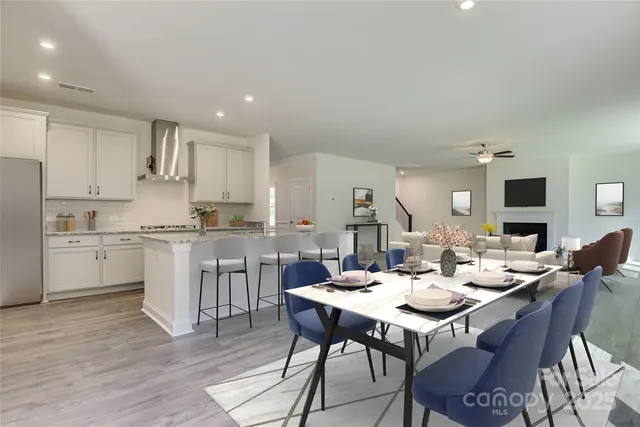 a open dining room with stainless steel appliances kitchen island granite countertop a stove a sink a dining table and chairs