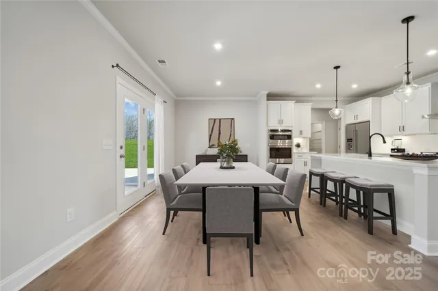 a kitchen with a dining table chairs and wooden floor