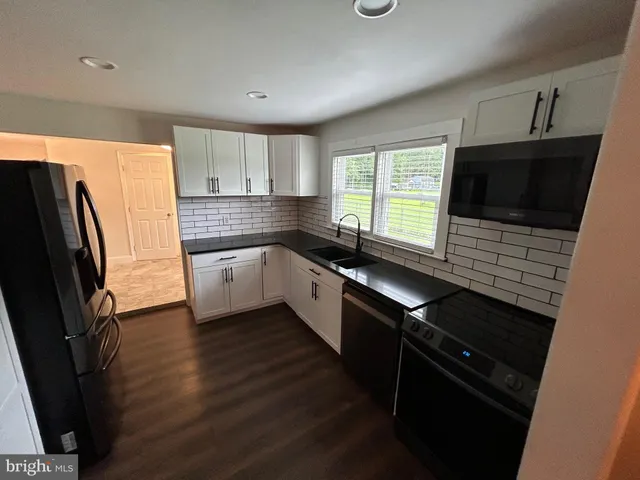 a kitchen with granite countertop a refrigerator a sink a stove and microwave