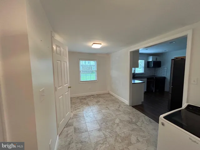 a view of empty room with kitchen and window