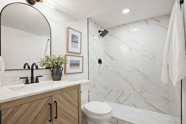 a bathroom with a sink a toilet a mirror and shower