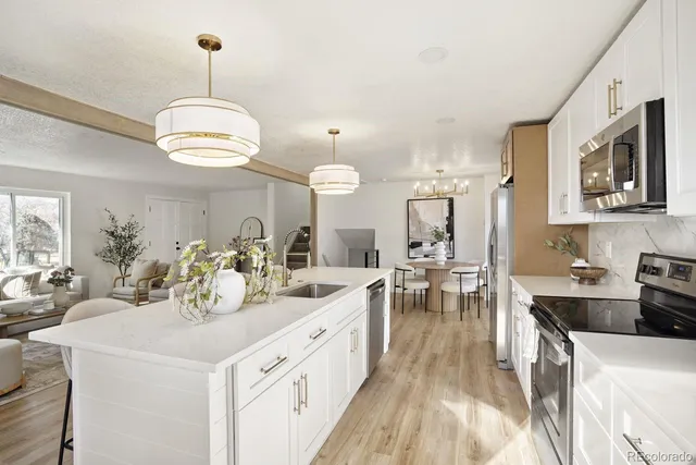 a large white kitchen with lots of counter space a sink dining table and chairs