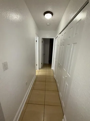 a view of a hallway with wooden floor and a shower