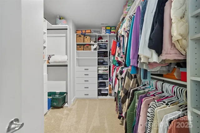 a view of walk in closet with clothes and shoes