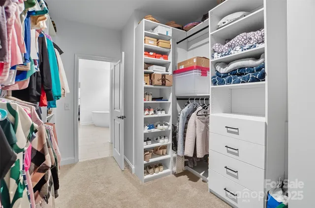 a view of walk in closet with clothes and shoes