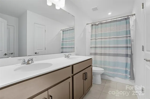 a bathroom with a sink toilet double vanity and shower