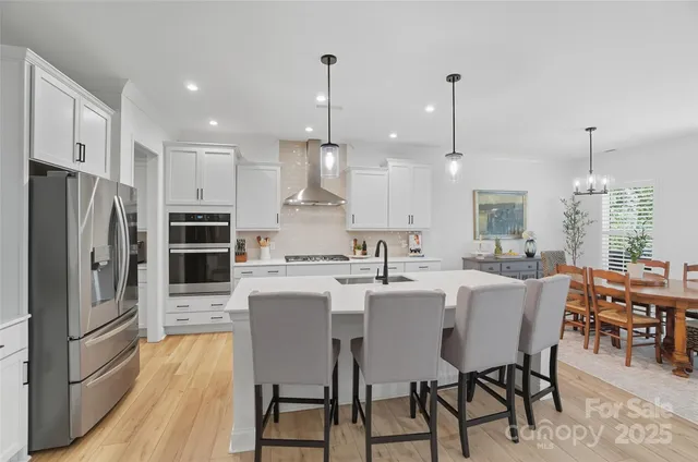 a kitchen with a dining table chairs refrigerator and microwave