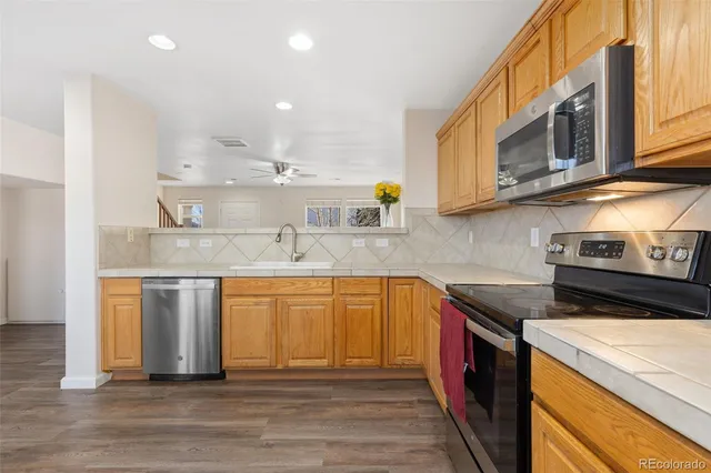 a kitchen with stainless steel appliances granite countertop a sink a stove and a wooden cabinets