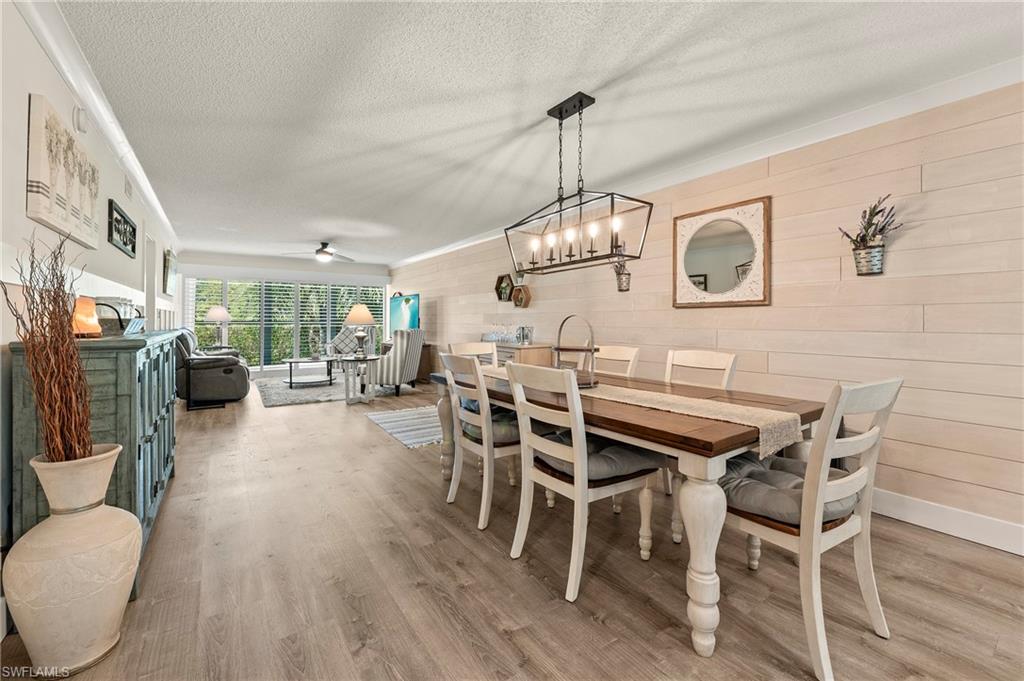 118 Palm Drive, Unit 9714 Naples, FL 34112 - Photo 1 of 24 Dining room with wooden walls, baseboards, ceiling fan with notable chandelier, wood finished floors, and a textured ceiling